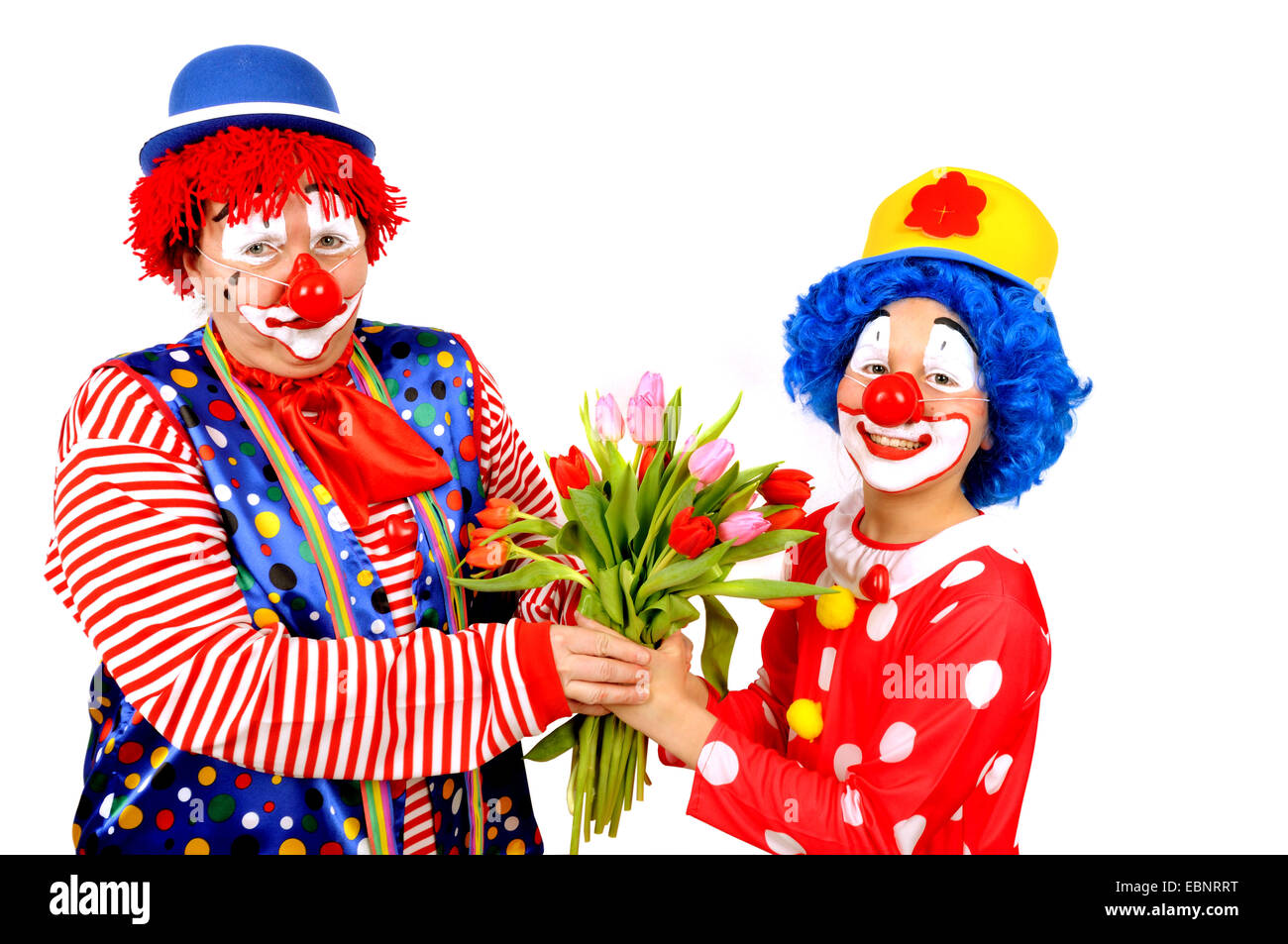 Mutter mit Sohn verkleidet als Clowns halten zusammen ein paar Tulpen Stockfoto