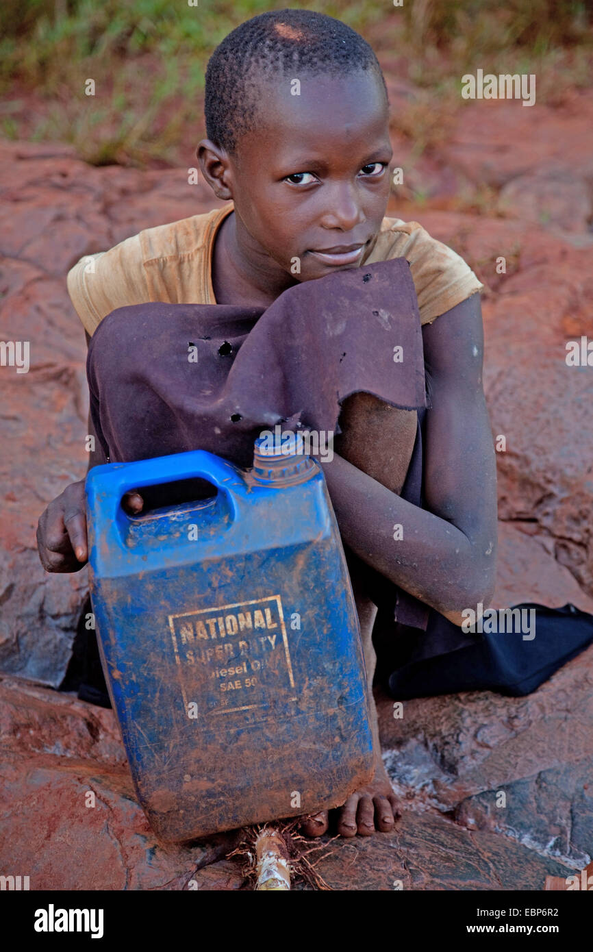 Mädchen sitzt am Ufer des Flusses Nil mit einer alten heavy-Duty Öl-Kanister, die sie benutzt, um Wasser, Uganda, Jinja zu holen Stockfoto