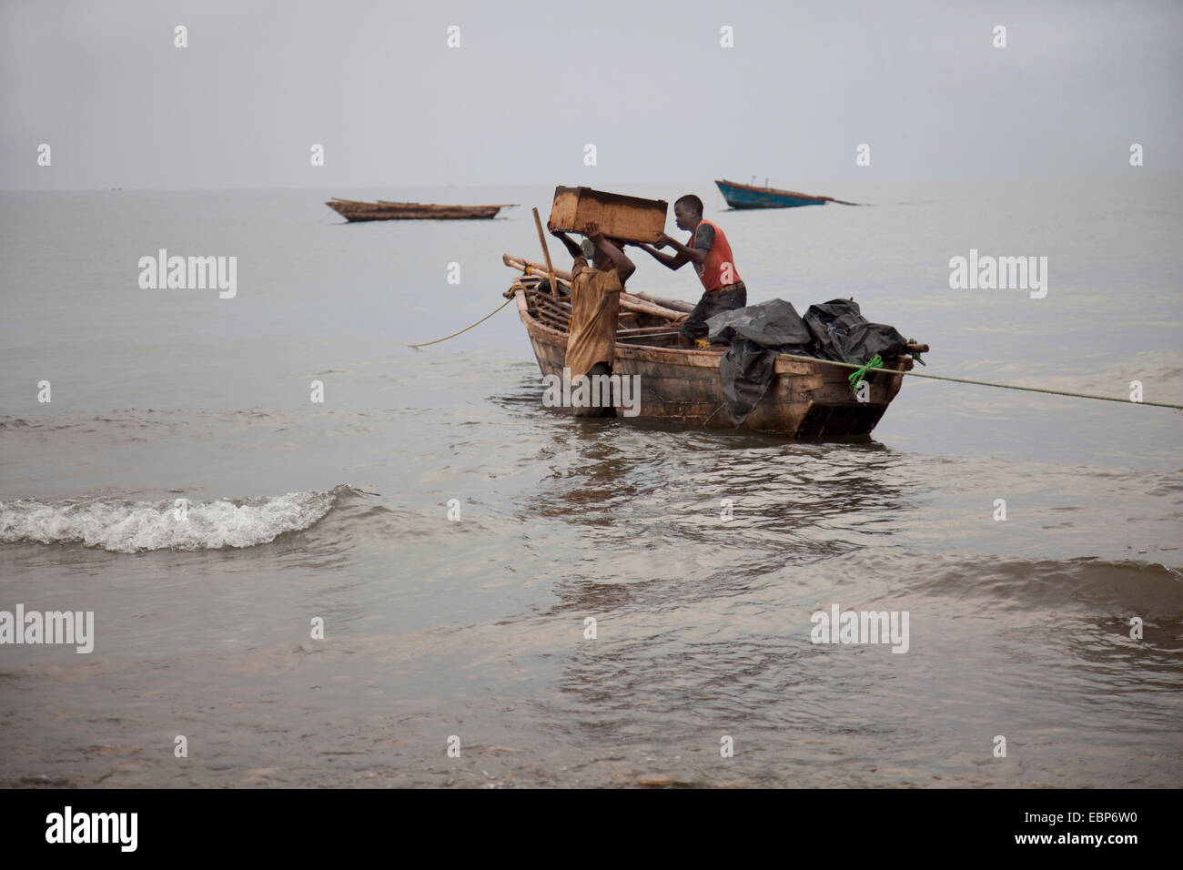 Junge mit Holzbox mit vor kurzem gefangen Fisch auf dem Kopf von einem Boot zum Ufer von wo es in die Hauptstadt, Burundi, Nyanza Lac, Mvugo, Nyanza Lac gebracht wird Stockfoto