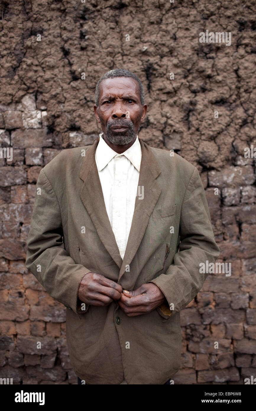 älterer Mann in einem Hemd und Jacke stand vor einem traditionellen Ofen in dem, den, den Schlamm Ziegel gebrannt werden, Burundi, Kabezi Stockfoto