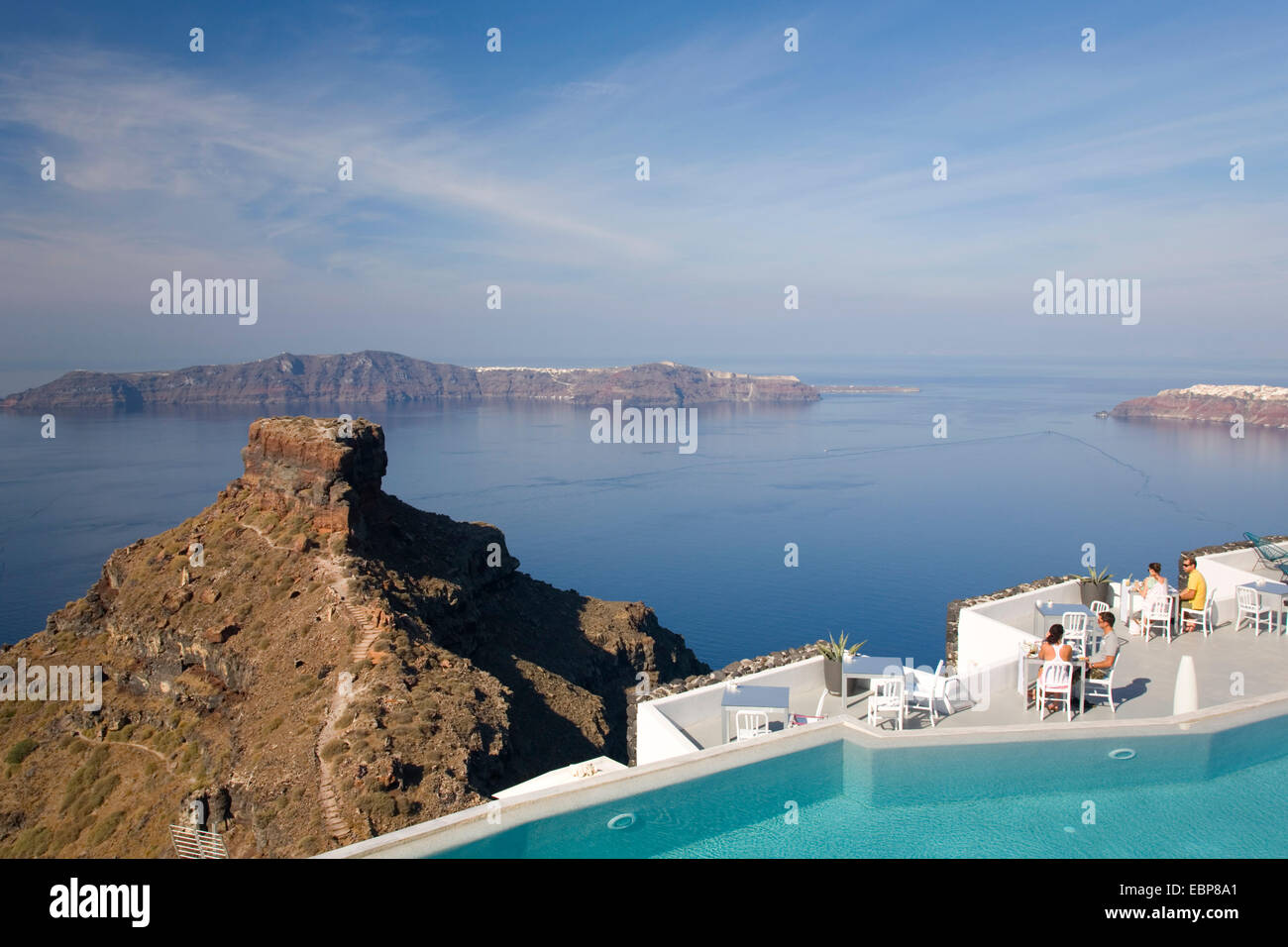 Imerovigli, Santorin, südliche Ägäis, Griechenland. Blick auf Skaros Rock und der Insel Thirasia Touristen beim Frühstück neben Pool. Stockfoto