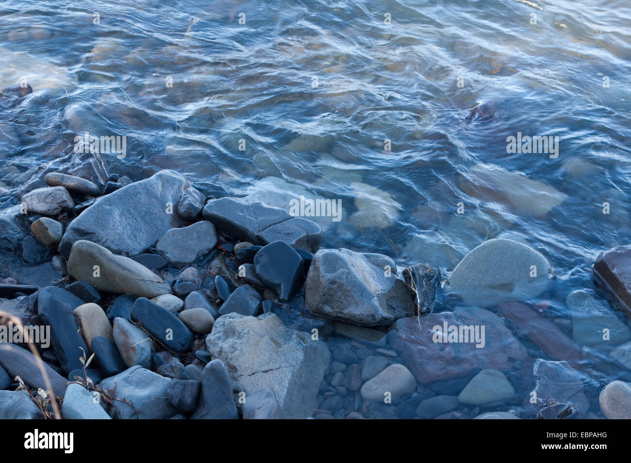 Steinen am Ufer. Der Wasserstrahl ist streicheln Steinen und unterstreicht ihre Farbe und Textur. Stockfoto