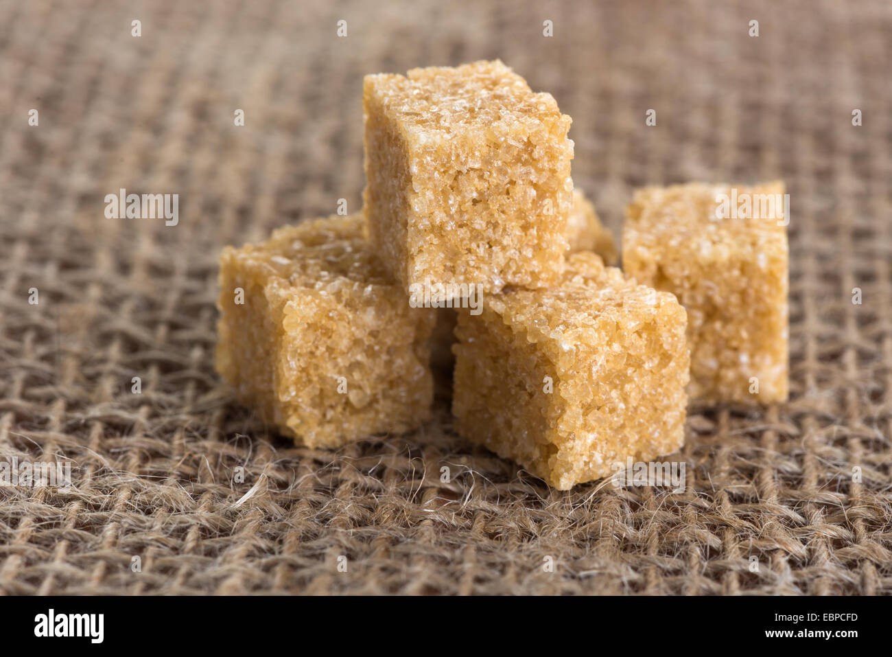 Würfel braunen Rohrzucker auf einem Hintergrund von Jute-Taschen Stockfoto