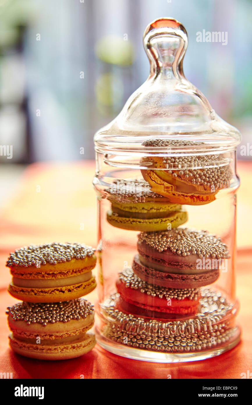 Funkelnde Makronen Cookies in einem Glas für die Feiertage orange Tischdecke Stockfoto