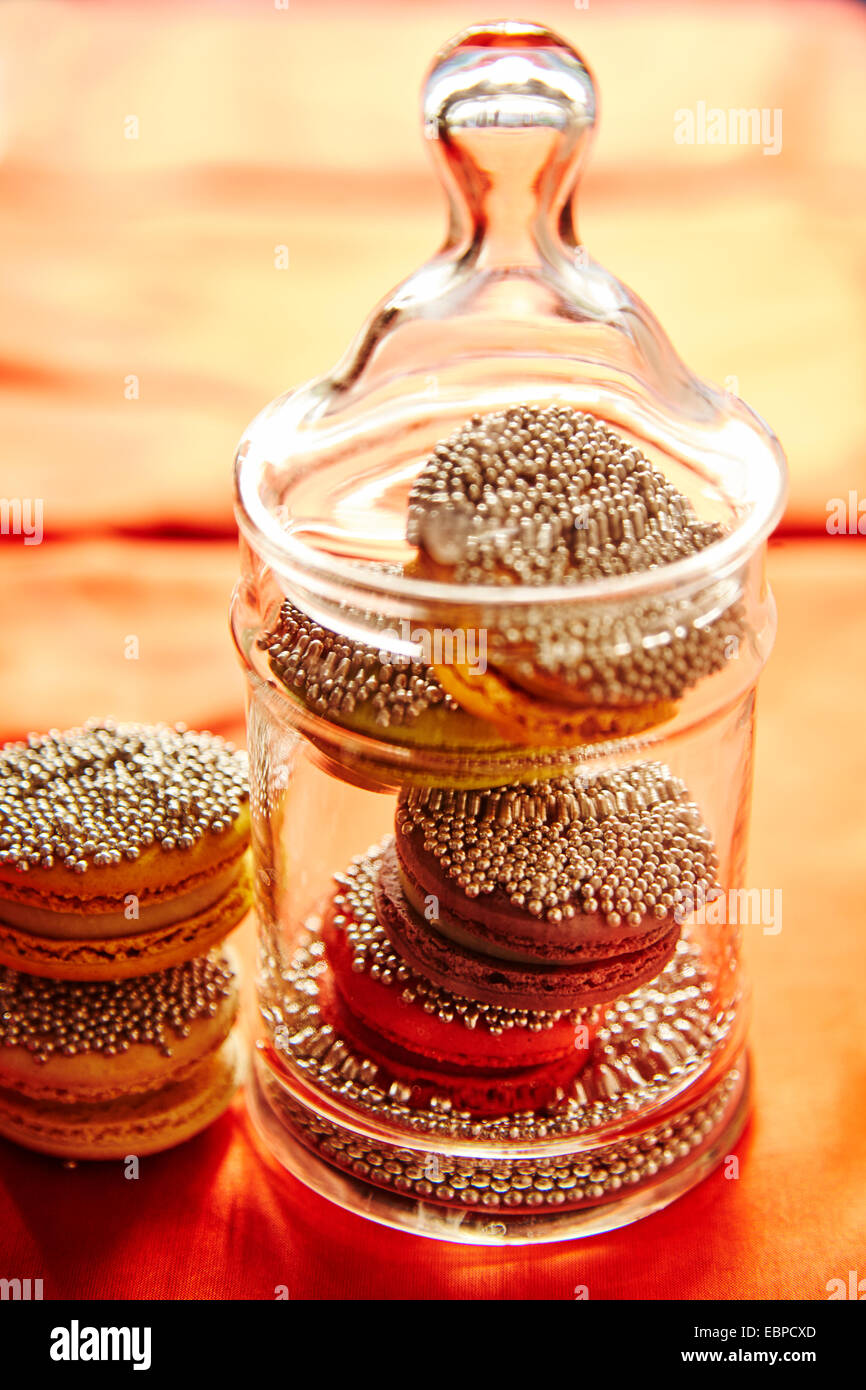 Funkelnde Makronen Cookies in einem Glas für die Feiertage orange Tischdecke Stockfoto