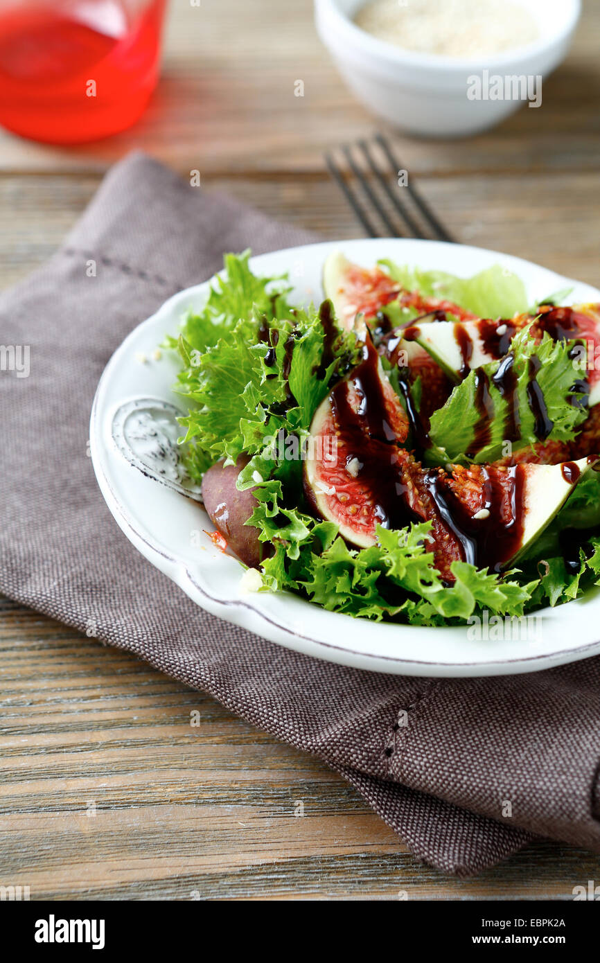 Salat mit Feigen, Salat und Balsamico-Sauce in einer weißen Schüssel, Essen auf einem hölzernen Hintergrund Stockfoto
