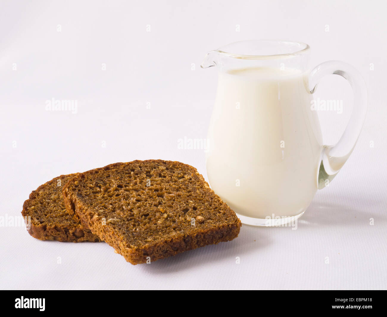 Milch und Scheiben Graubrot Stockfoto