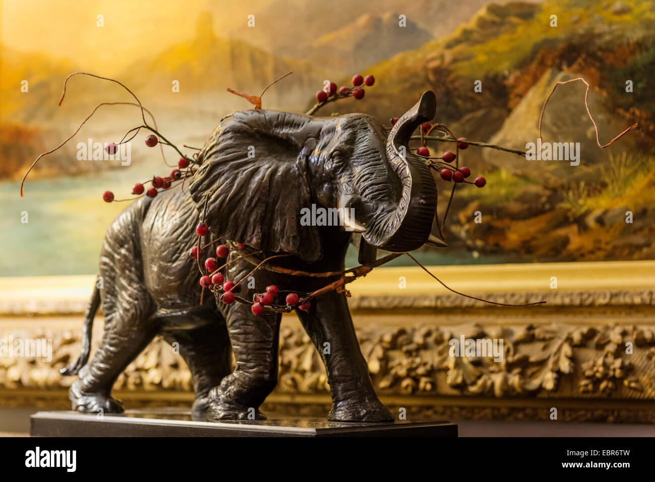 ein Zweig der Stechpalme verleiht eine Statue eines Elefanten eine festliche Note. Stockfoto