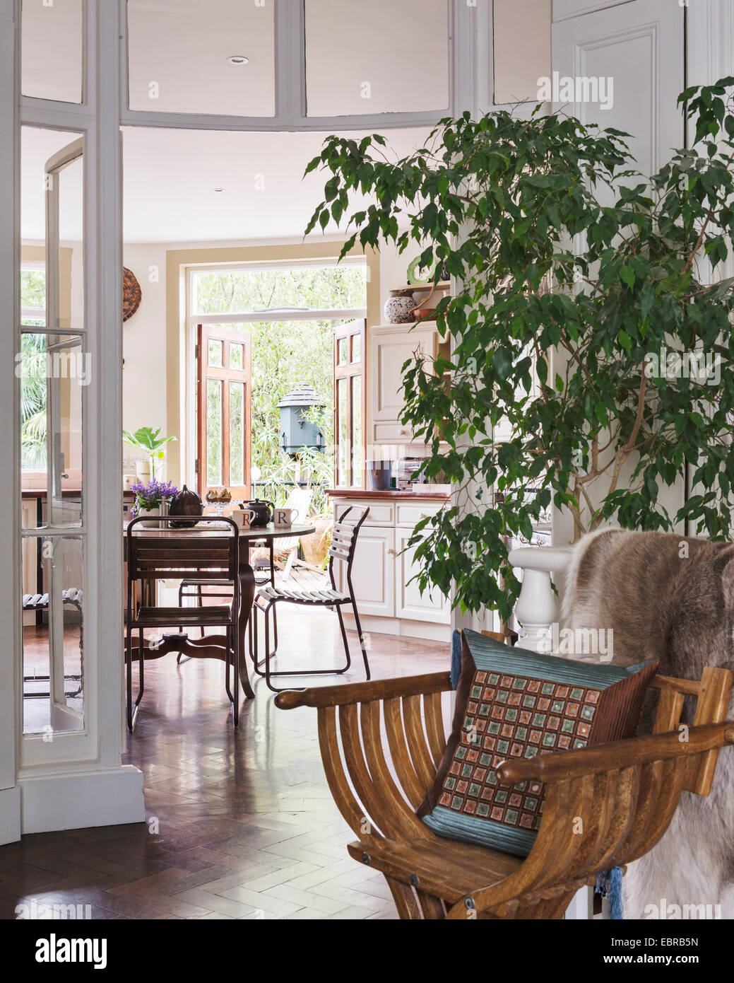 Antiker Holzstuhl und Hausanlage und Blick durch Flügeltüren zum Garten Stockfoto