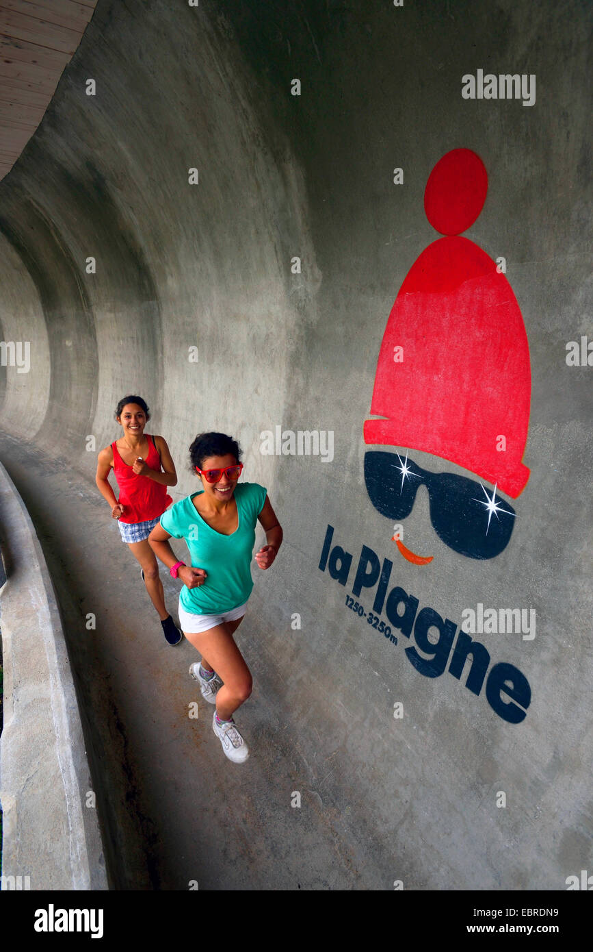 zwei junge Frauen laufen auf der Bobbahn im Sommer, Frankreich, Savoyen, La Plagne Stockfoto