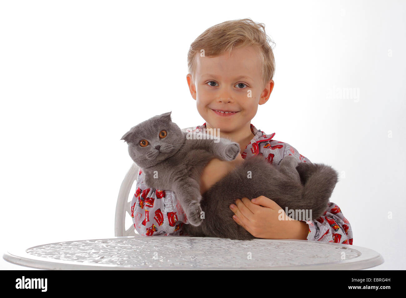 Hauskatze, Hauskatze (Felis Silvestris F. Catus), lächelndes Kind im Schlafanzug mit Katze auf arm Stockfoto