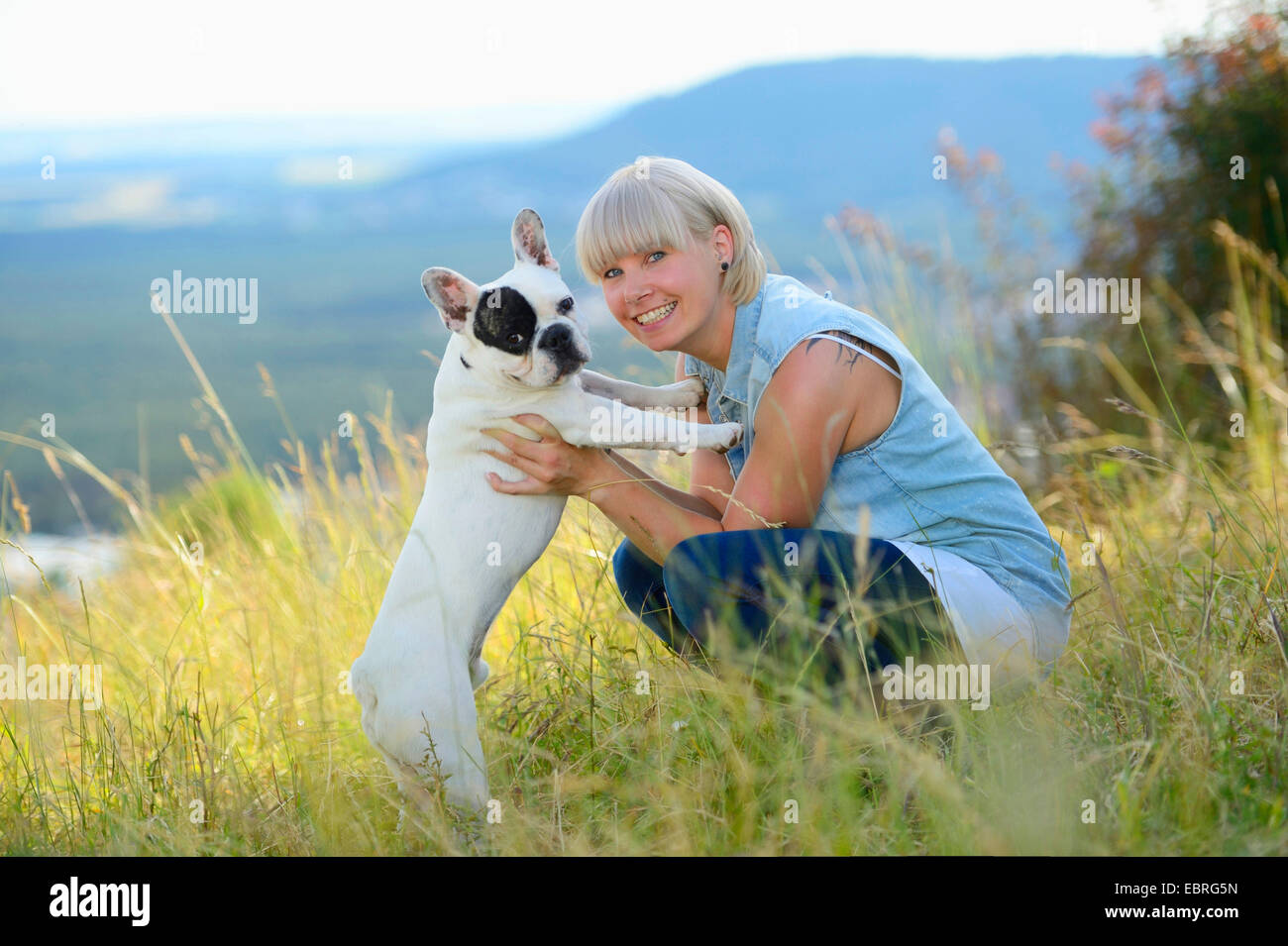 Französische Bulldogge (Canis Lupus F. Familiaris), Frau und Hund umarmt auf einer Wiese, Deutschland Stockfoto