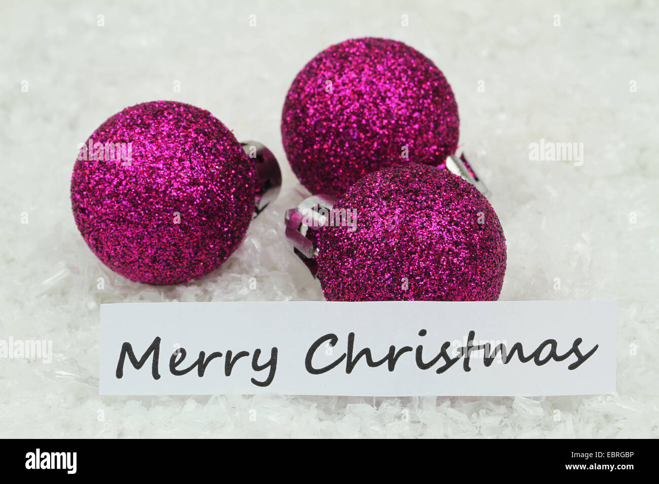 Lustige Weihnachtskarte mit lila Kugeln auf Schnee Stockfoto