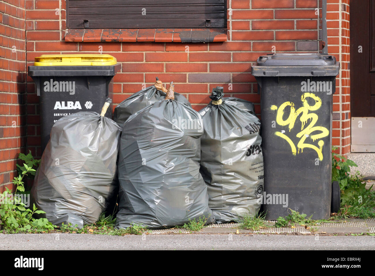 Mülltonnen und Mülltüten vor einer Fassade, Deutschland, Nordrhein-Westfalen, Ruhrgebiet Stockfoto