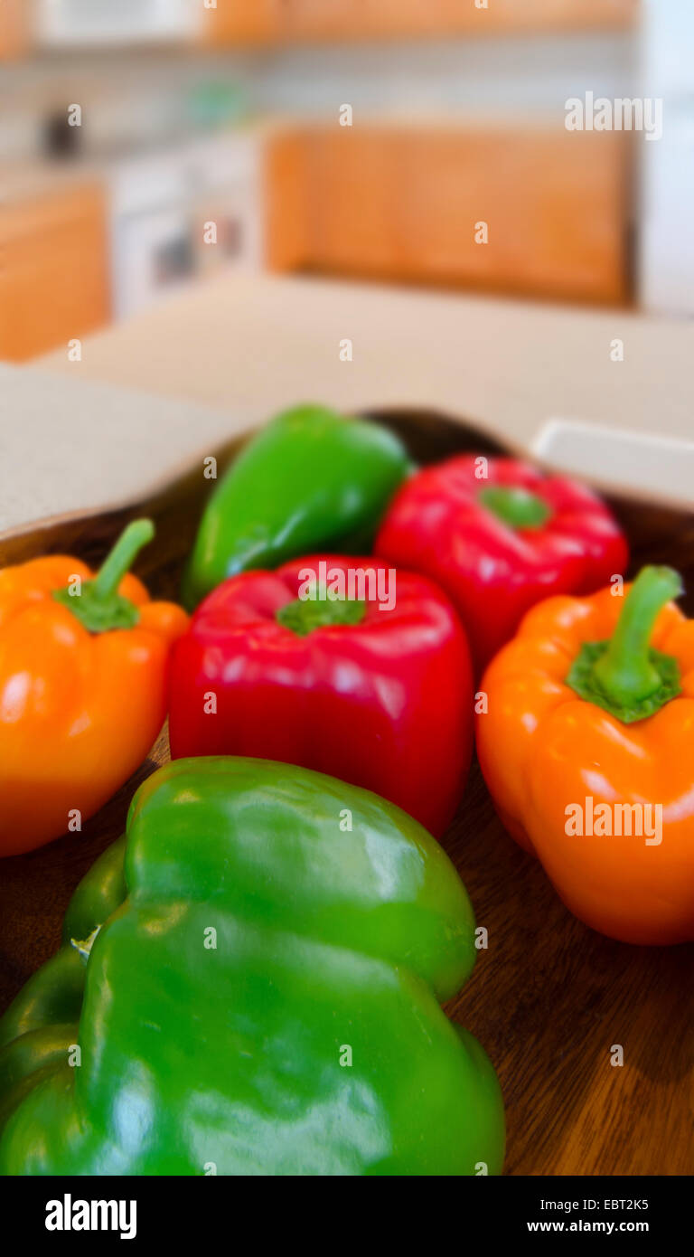Schüssel mit Paprika: rot, grün und orange Paprika in einem Holz Schale in einer modernen Küche. Stockfoto