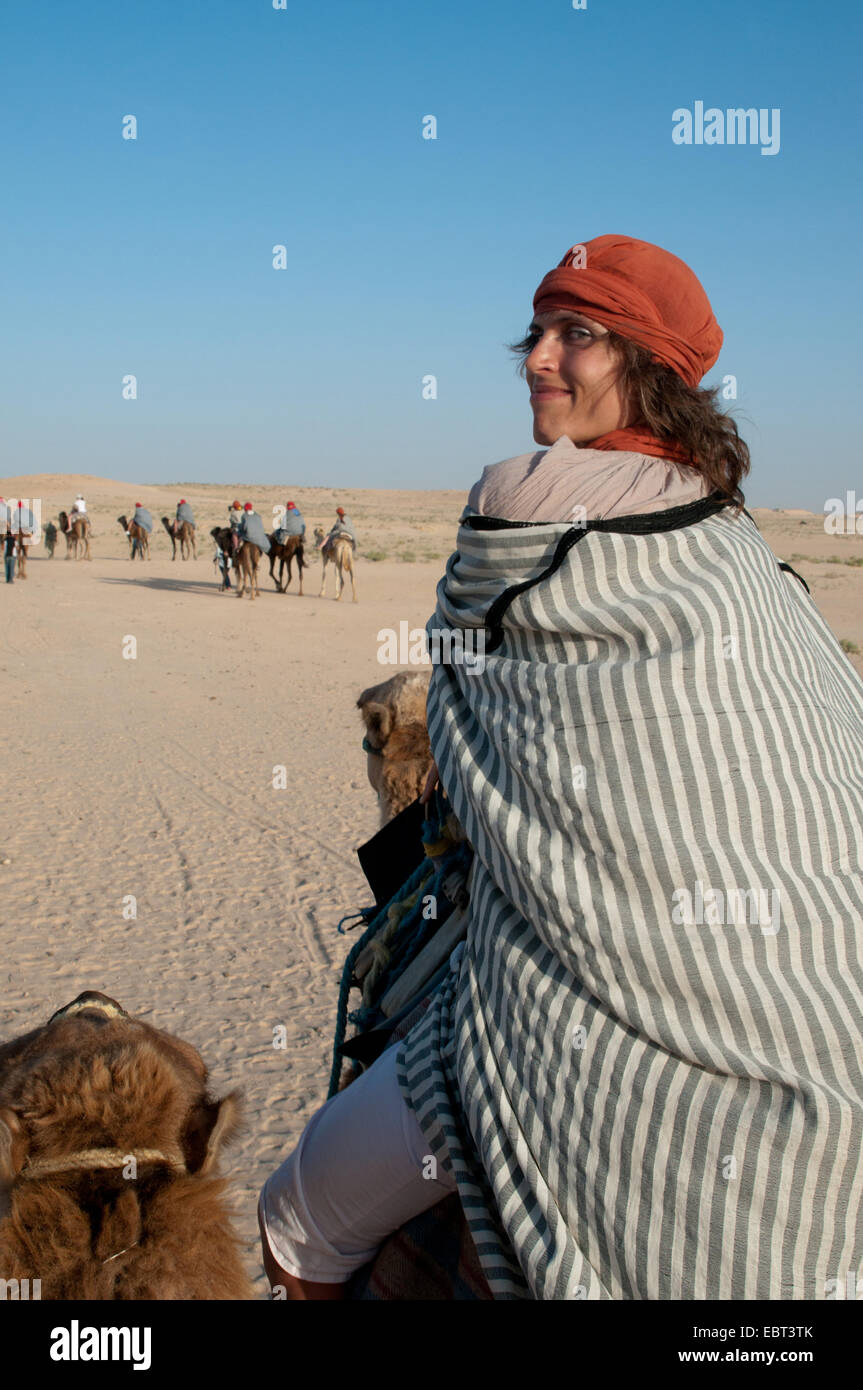 Dies ist eine Reise auf Kamel in der Wüste Sahara. Die Frau gekleidet in der Beduinen Gestalt drehte sich um und Lächeln. Stockfoto