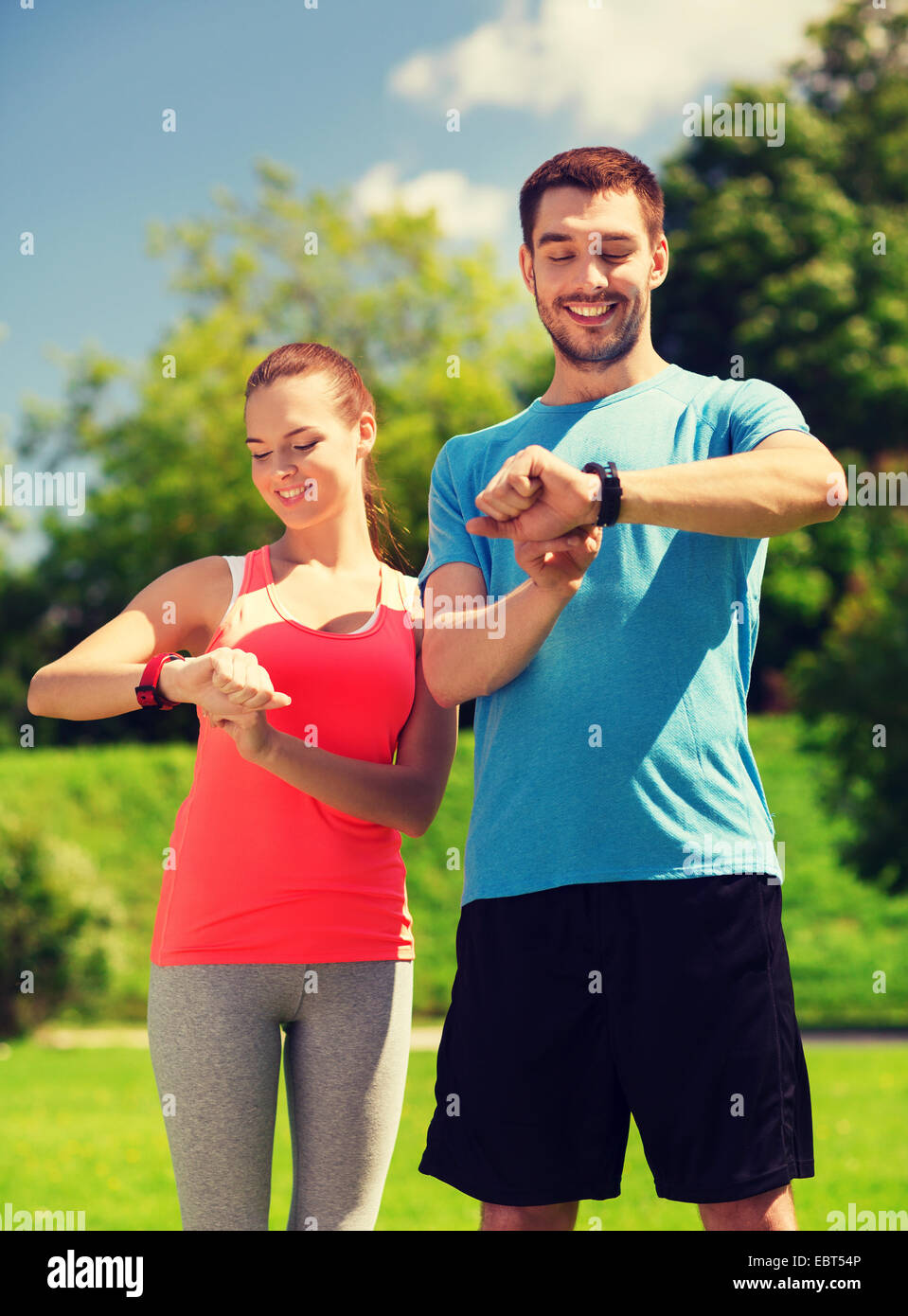 lächelnde Menschen mit Herzfrequenz-Uhren im freien Stockfoto