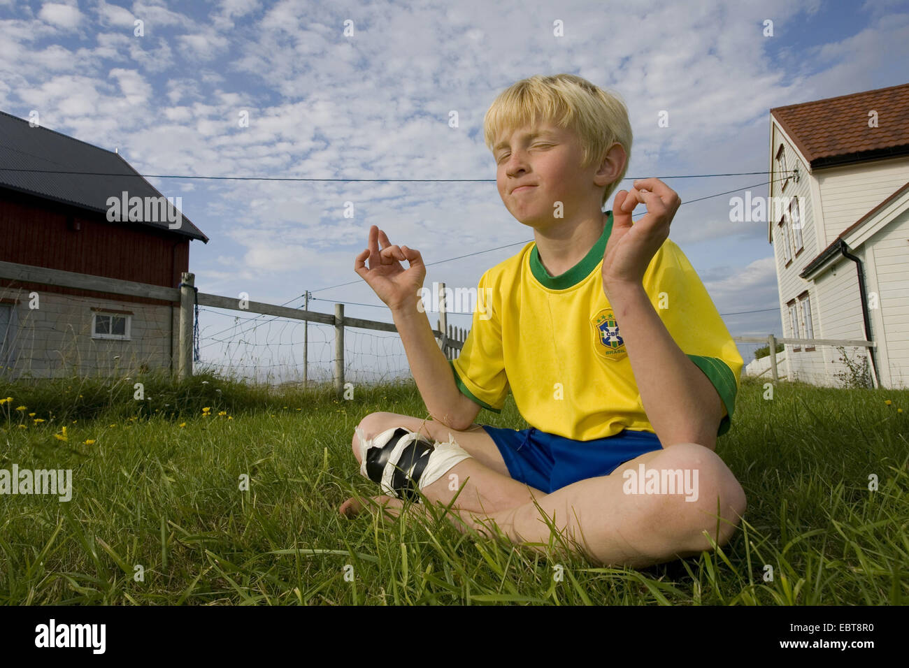 kleiner Junge spielt im Lotussitz, Norwegen Stockfoto