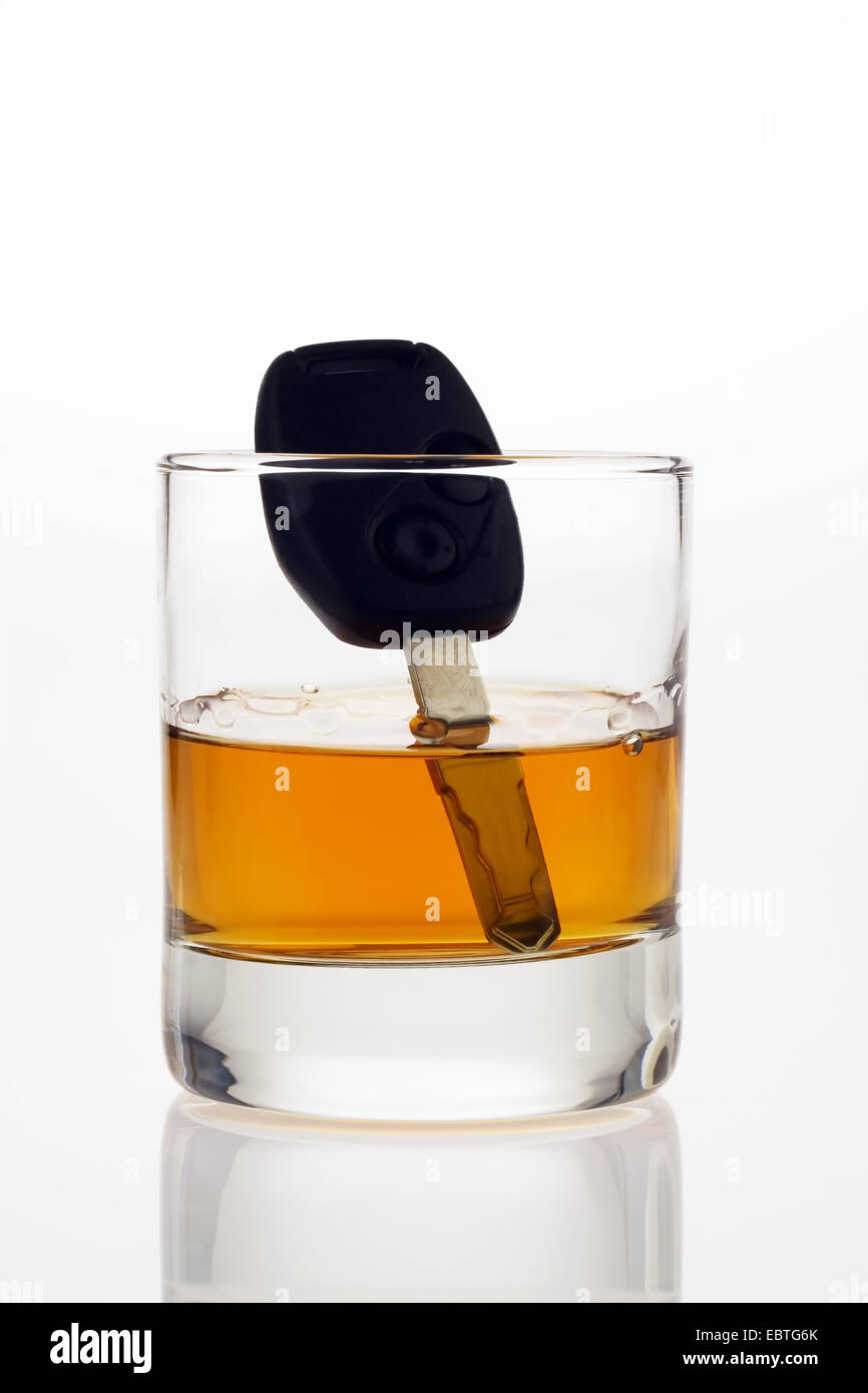 Autoschlüssel in einem Glas Alkohol sinkt Stockfoto