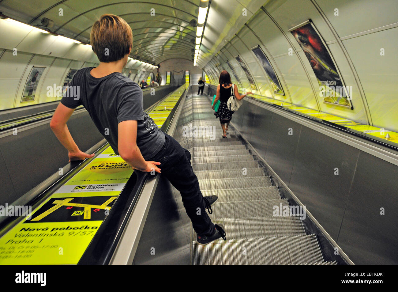 11 Jahre alter Junge sitzt auf den Handlauf einer Rolltreppe zur Metro Prag, Tschechische Republik, Prag Stockfoto