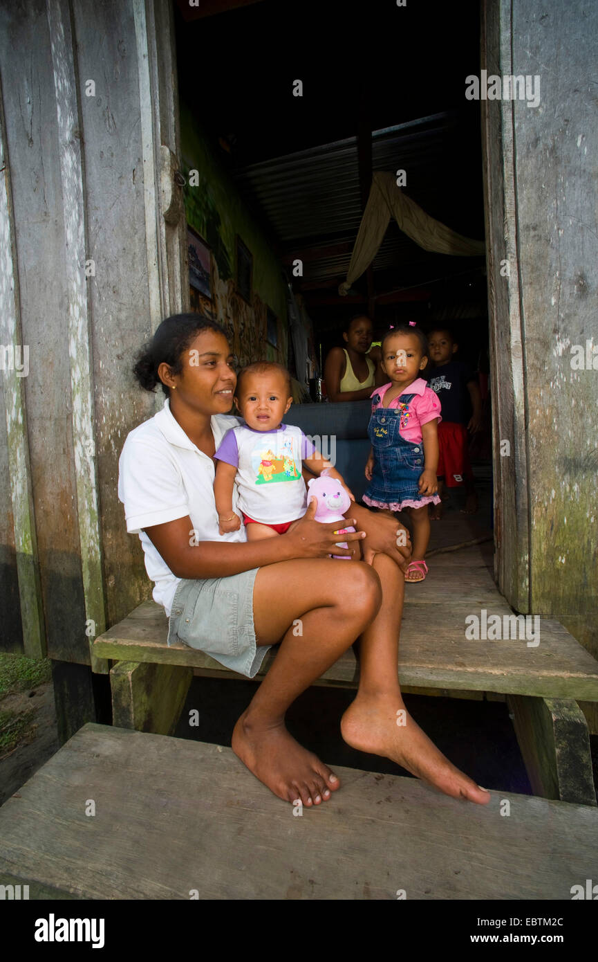 Gebürtige Inderin mit einem Baby sitzen vor der Haustür ihres Holzhauses, Honduras, La Mosquitia, Las Marías, Gracias a Dios Stockfoto