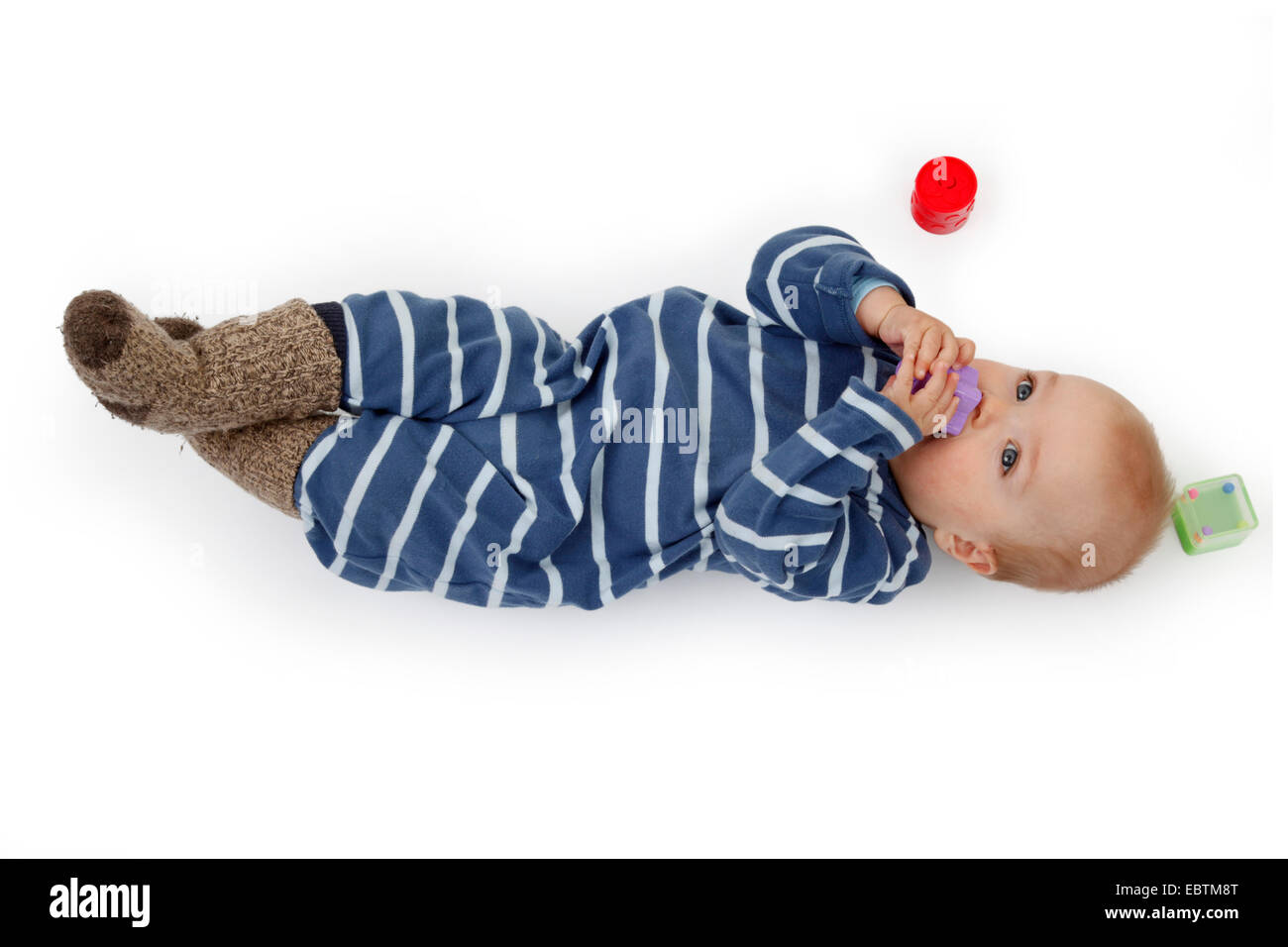 kleines Kind im Strampler auf dem Boden liegen und spielen mit Baby-Spielzeug Stockfoto