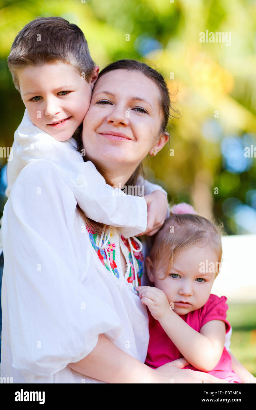 glückliche junge Mutter mit ihren kleinen Kindern gegen ihr kuscheln im ...