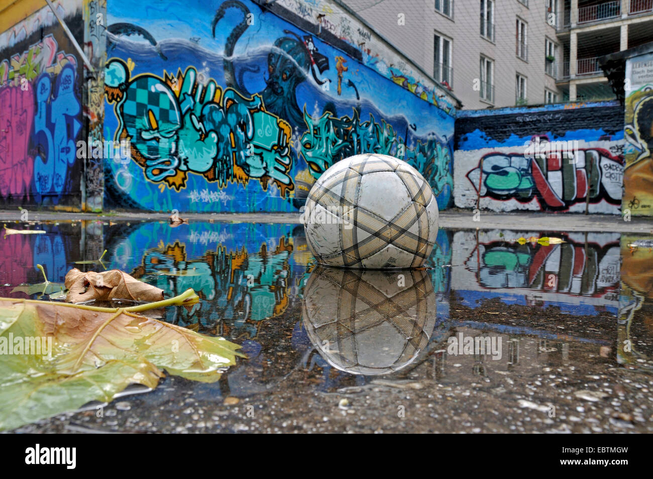 vergessen Fußball liegen in einer Pfütze vor Graffitiwand, Deutschland, Nordrhein-Westfalen, Köln Stockfoto
