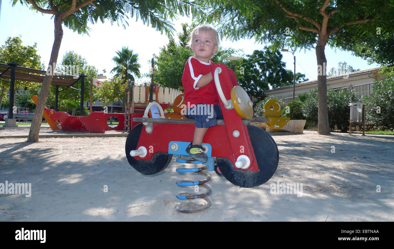 kleiner Junge sitzt auf einem Springer auf dem Spielplatz Stockfoto