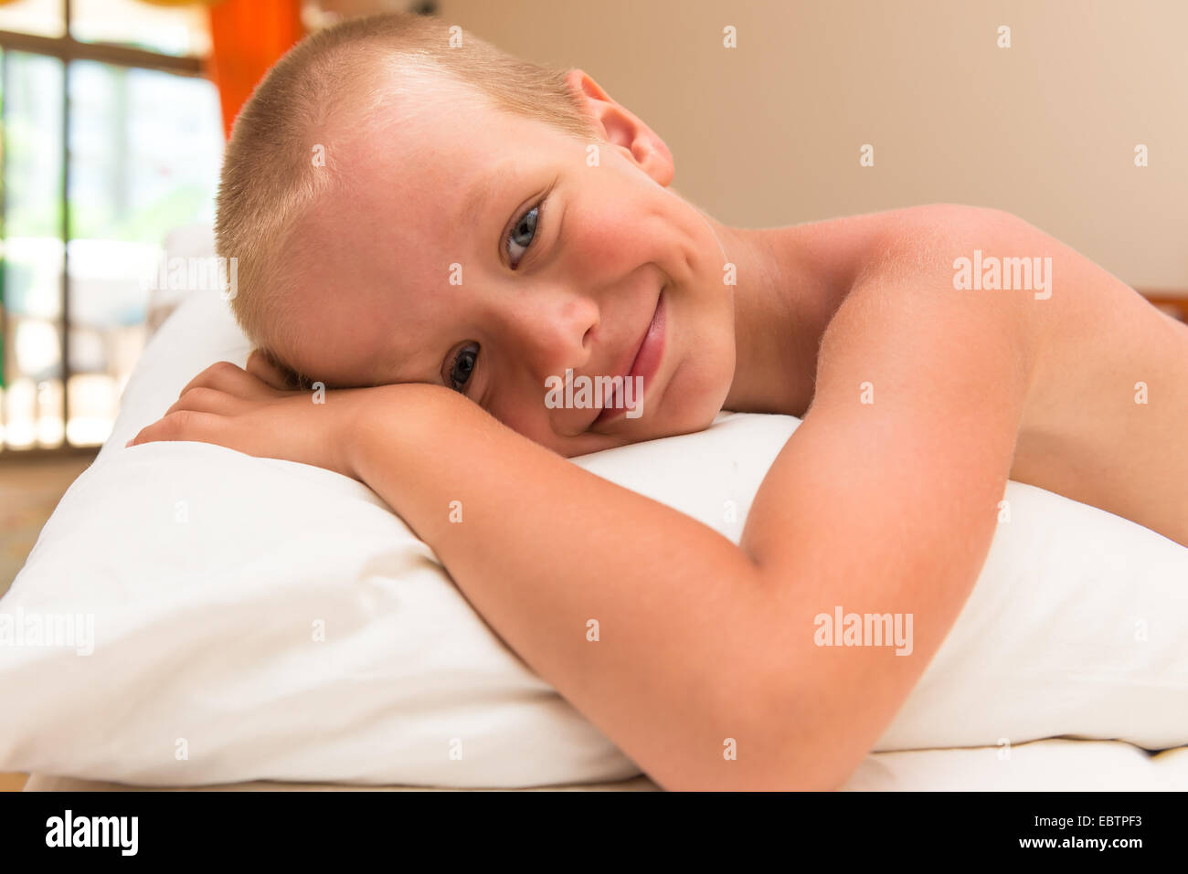 glücklich lächelnde Knabe auf einem Kissen im Bett liegend Stockfoto