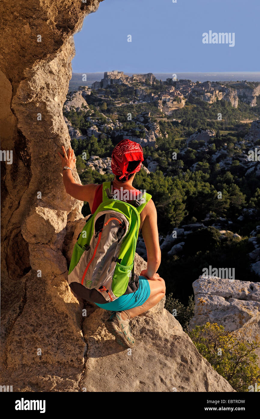 weibliche Wanderer neben einem Felsen hocken und die Aussicht genießen, Baux de Provence, Bouches-du-Rhône, Provence, Frankreich Stockfoto