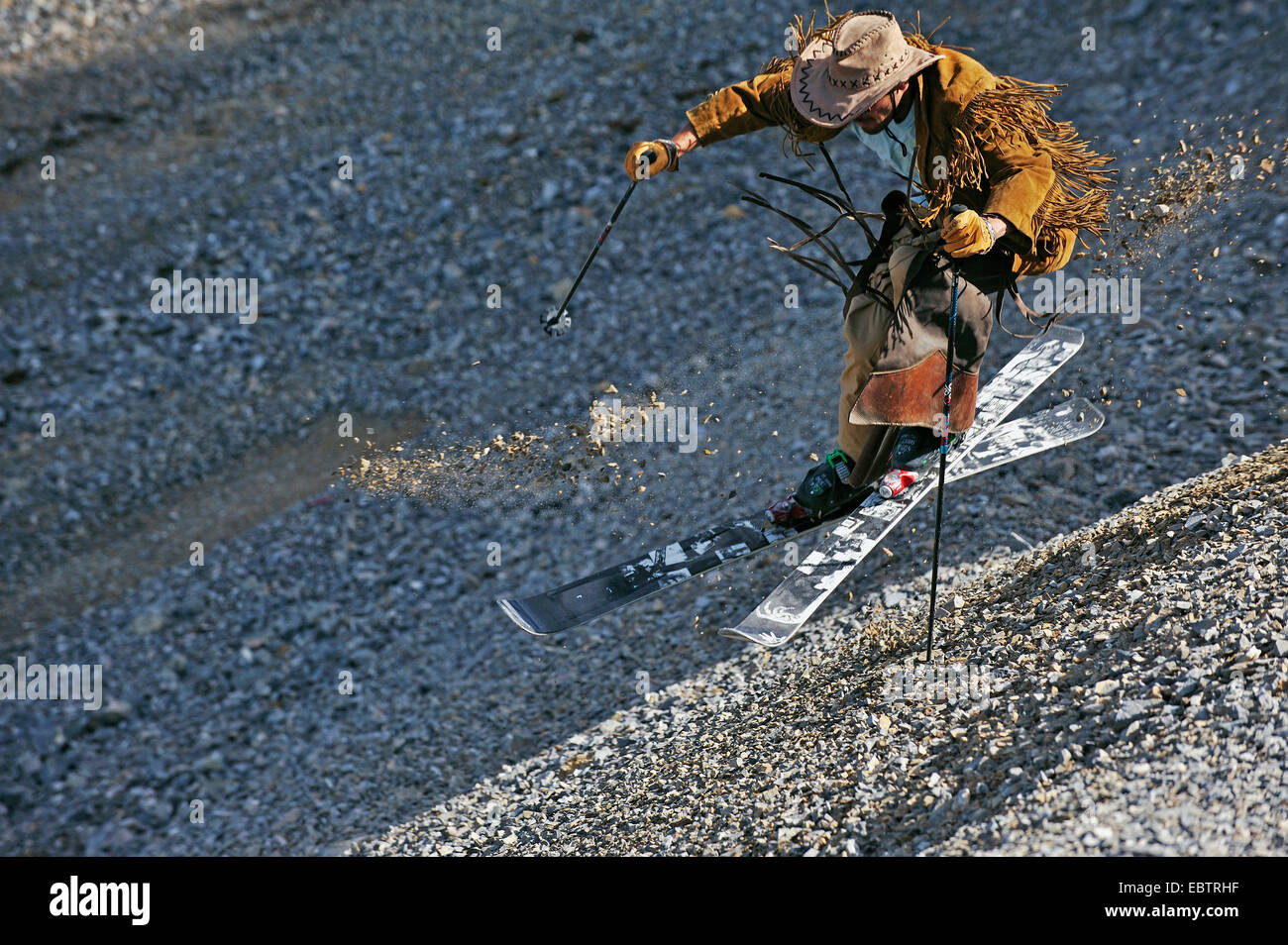 Freeride-Skifahrer verkleidet als Cowboy auf Schotter Piste bergab Stockfoto