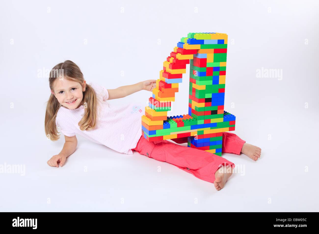 vier-jährigen Mädchen mit einer großen Zahl "4" aus Legosteinen gebaut Stockfoto