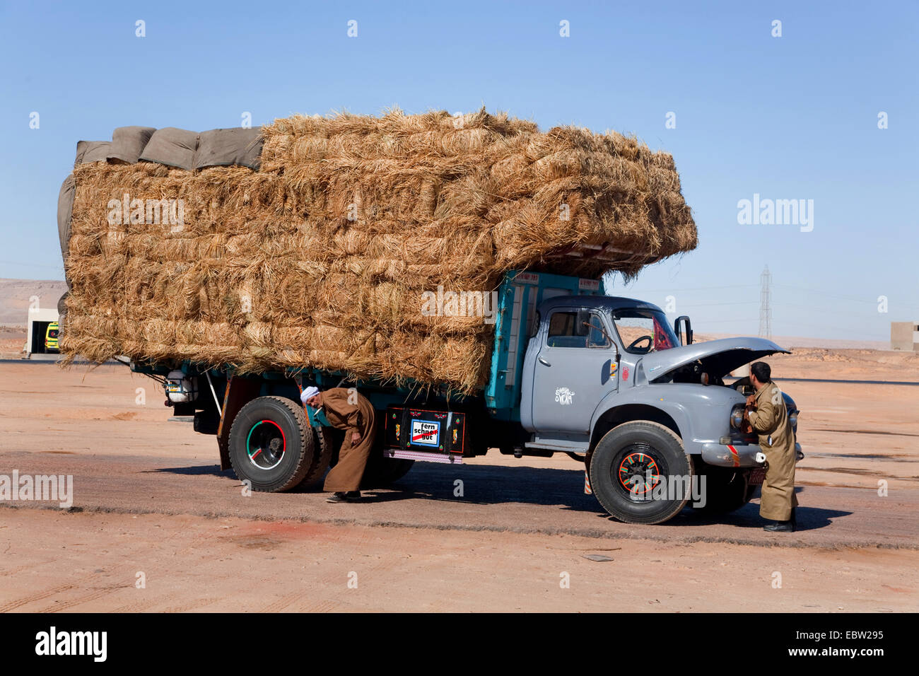 LKW mit Heuballen und Kfz-Mechaniker vor der Motorhaube in der ägyptischen Wüste, Ägypten, Assuan Stockfoto