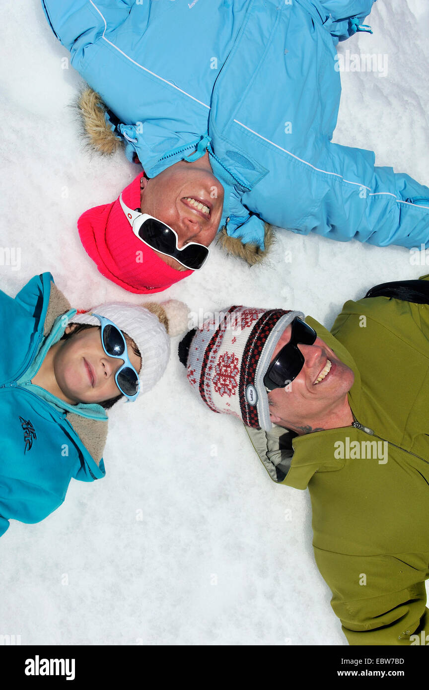 Familie im Winterurlaub im Schnee mit den Köpfen aneinander, Frankreich glücklich liegen Stockfoto