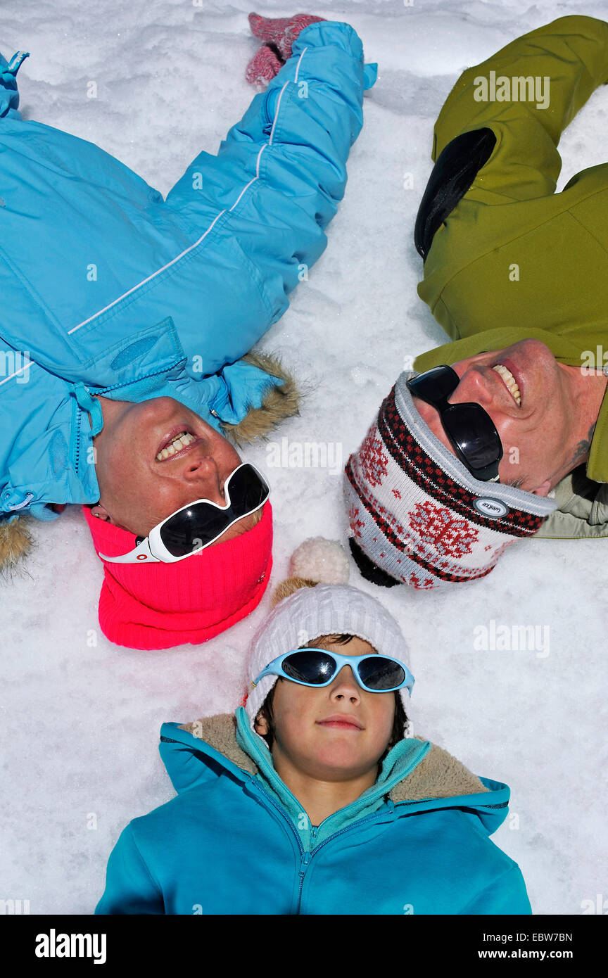 Familie im Winterurlaub im Schnee mit den Köpfen aneinander, Frankreich glücklich liegen Stockfoto