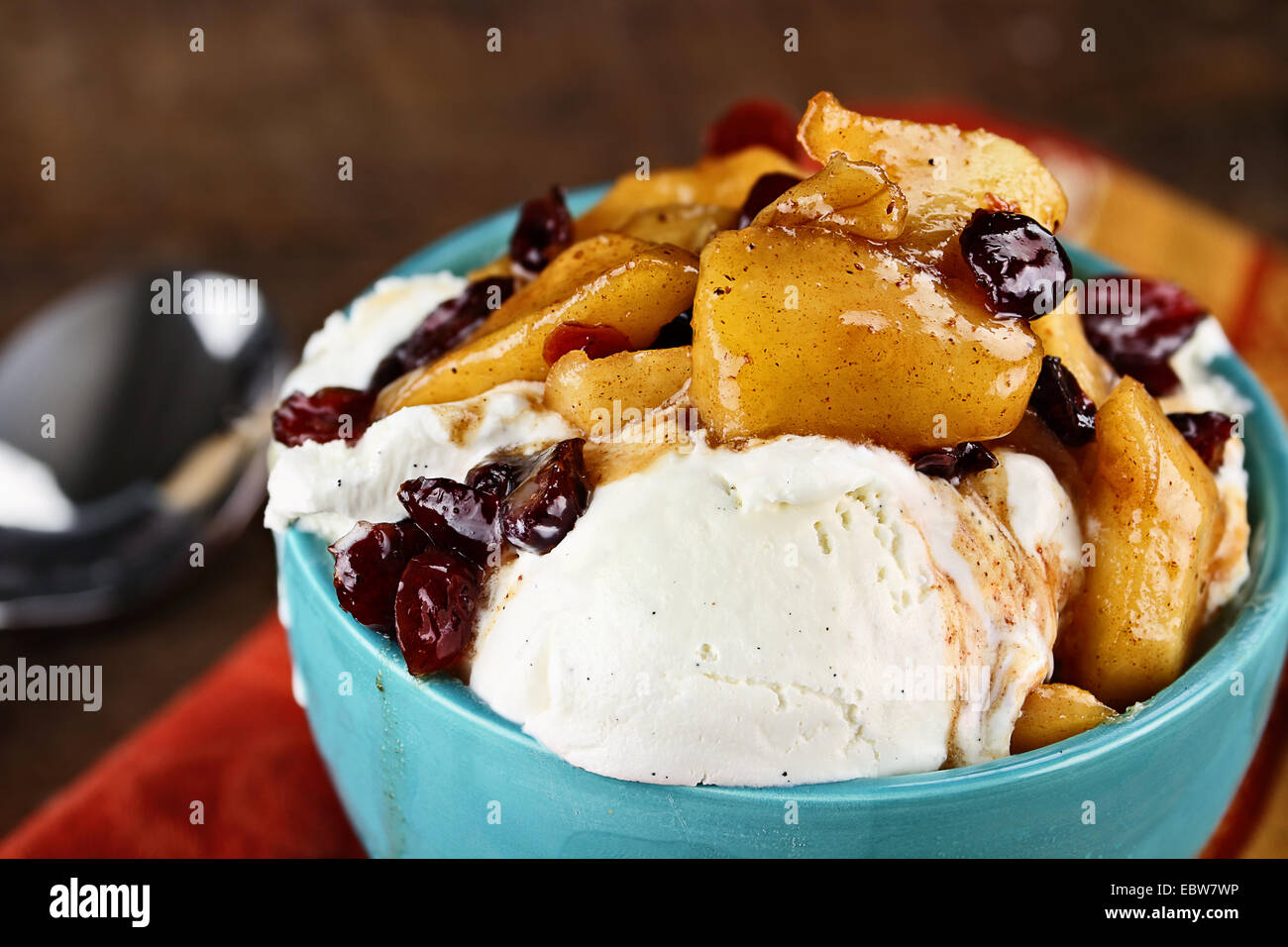 Schüssel reichen cremigen Vanilleeis garniert mit einem Apfel und Cranberry-Sauce mit extrem geringen Schärfentiefe. Stockfoto