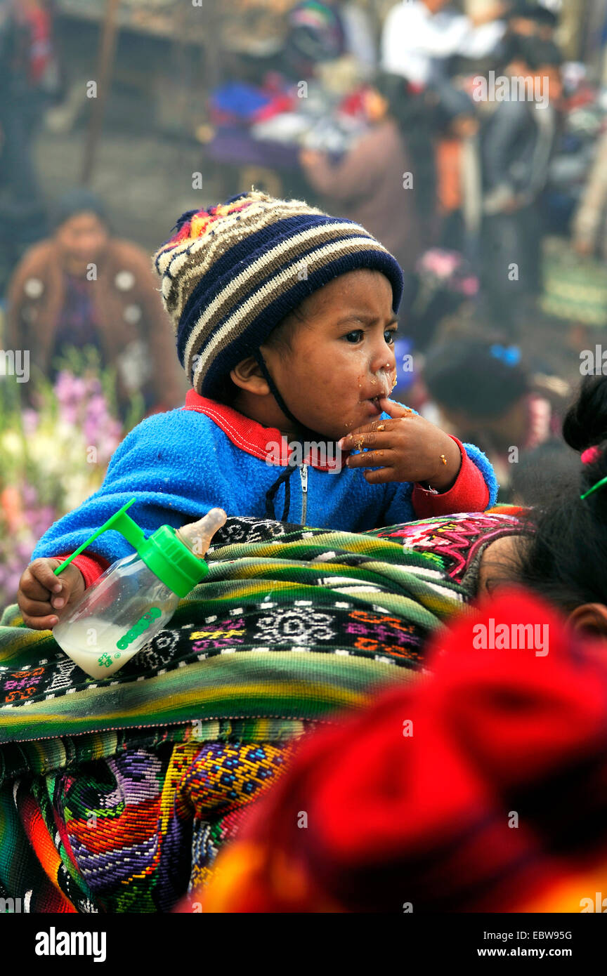 Kind mit Trinkflasche in der Hand auf Mutters Rücken, Guatemala Stockfoto