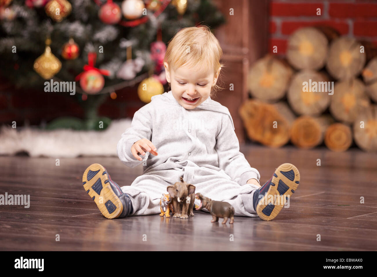 Fröhliche kleine Junge spielt mit seinem Spielzeugtiere Weihnachtsbaum Stockfoto