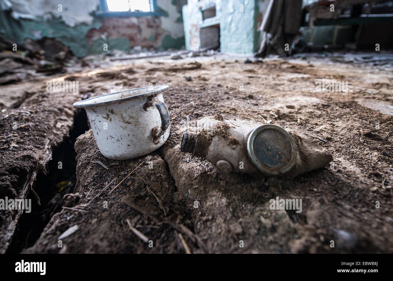 Metall-Becher und Gasmaske im alten Holzhaus in Wüstung Stechanka, Sperrzone von Tschernobyl, Ukraine Stockfoto