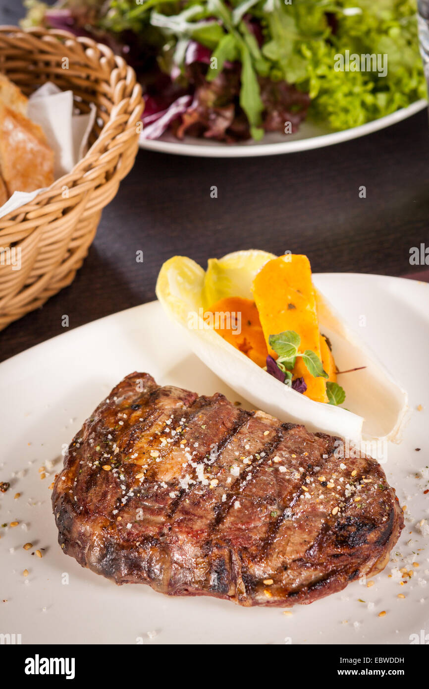 Lecker gegrilltes Rindersteak mit einem gezwirbelten Stück Butter und ein Zweig frischer Rosmarin garniert und serviert auf einem weißen Teller, enge u Stockfoto