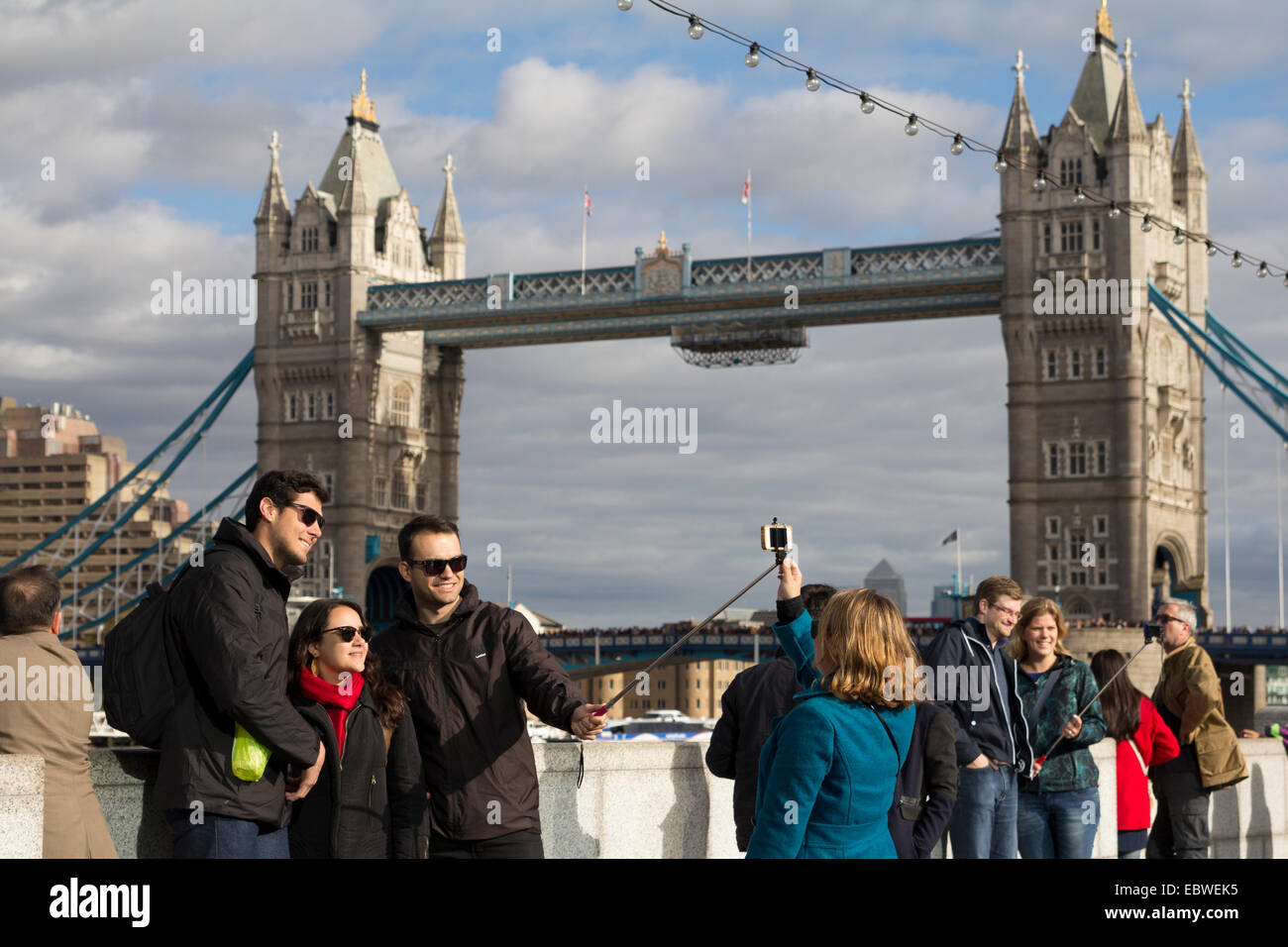 Touristen, die unter Selfies mit Hilfe eines Selfie Sticks durch den Tower of London, South Bank, UK Stockfoto