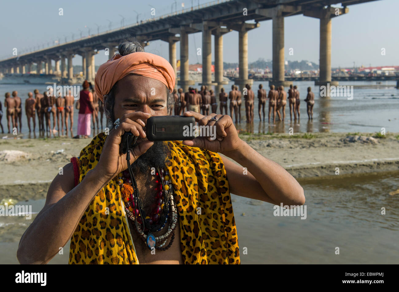 Shiva Sadhu, heiliger Mann, mit dem Fotografieren mit seinem Handy auf die Sangam, dem Zusammenfluss der Flüsse Ganges Stockfoto