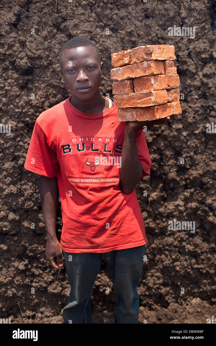 Bildnis eines Knaben mit einem Stapel von Bricks die gebildet von Schlamm vor Ort und in einem traditionellen Ofen verbrannt Burundi, Kabezi, Kabezi Stockfoto