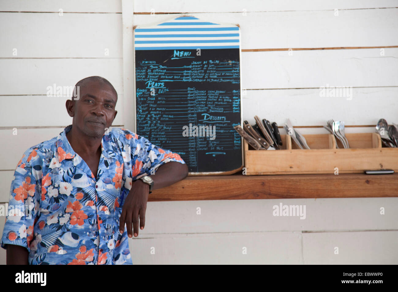 Mann, der an einer Theke mit Besteck und Menü, Burundi, Bujumbura Mairie, Bujumbura Stockfoto