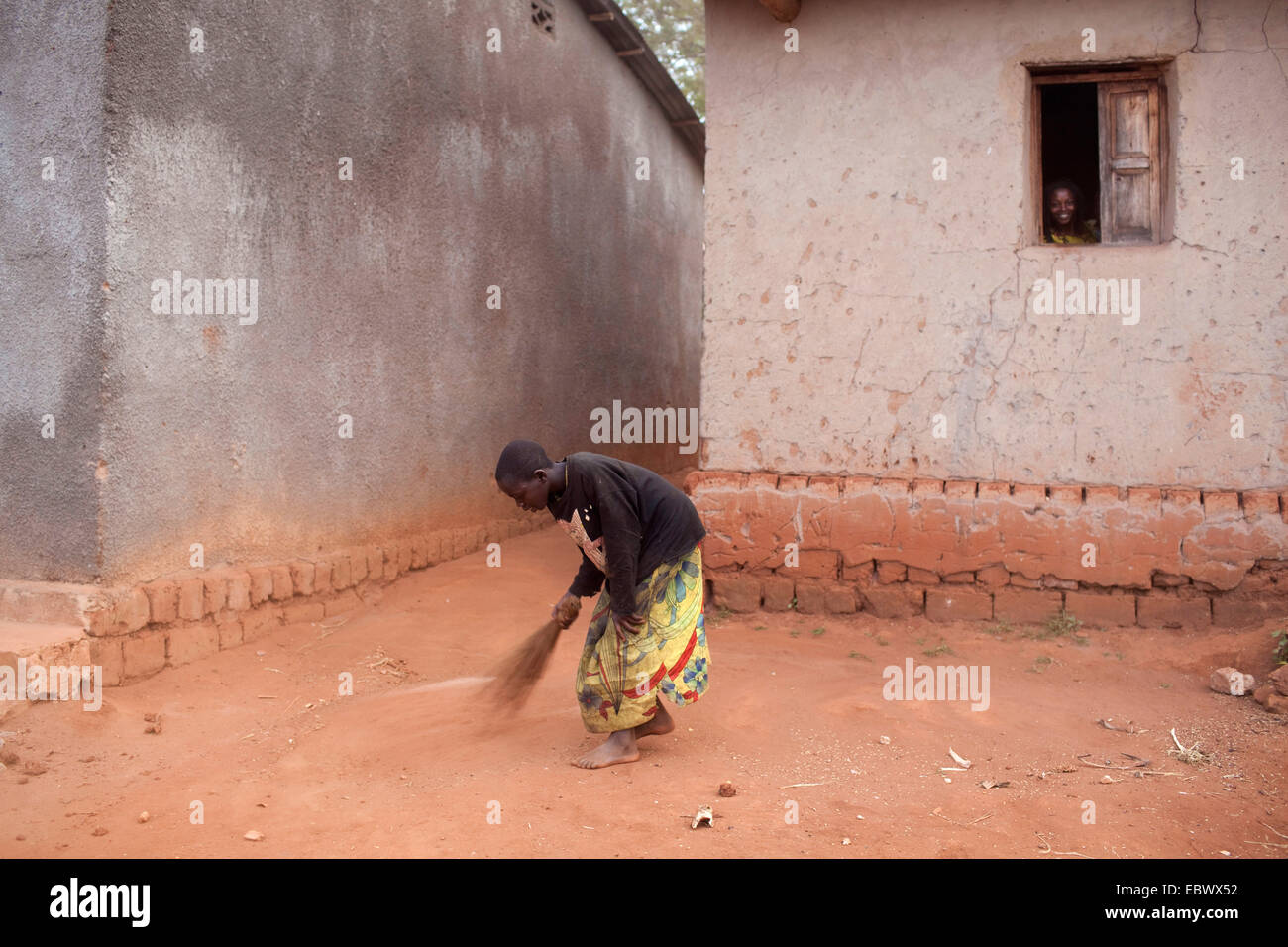 Mädchen fegen Hof eines Hauses, Burundi, Karuzi, Buhiga Stockfoto