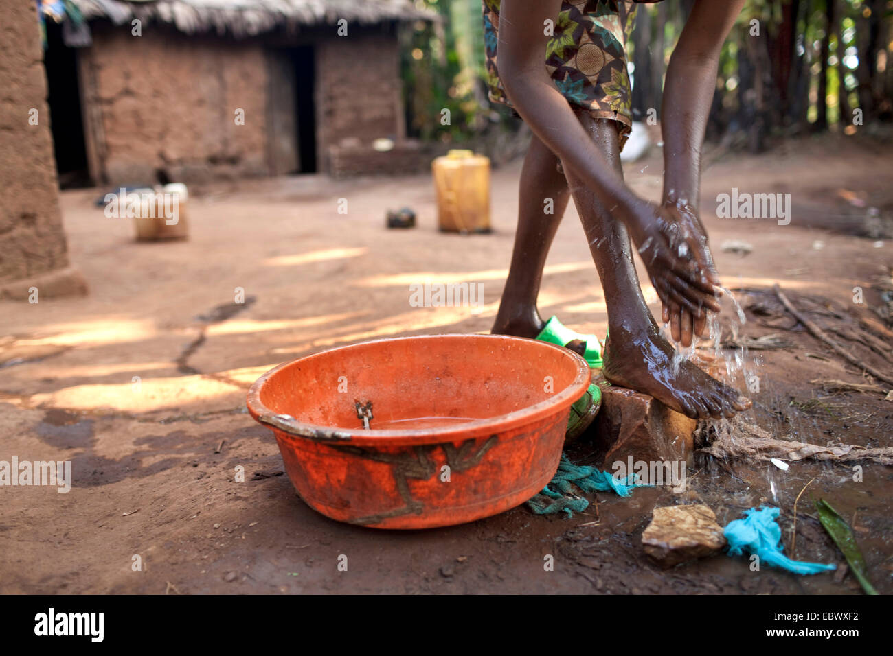 junge Frau in traditioneller afrikanischer Kleidung waschen sich vor ihrem Lehmhaus am Morgen, Burundi, Karuzi, Buhiga Stockfoto