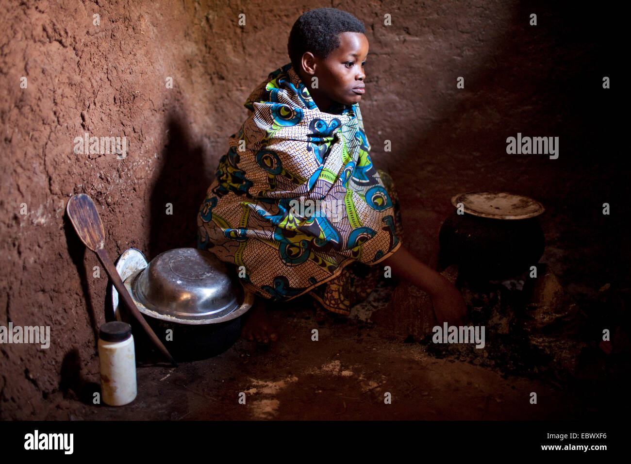 Frau in traditioneller Kleidung, die Zubereitung einer Mahlzeit auf dem Küchenboden von einem bescheidenen Lehmhaus, Burundi, Karuzi, Buhiga Stockfoto