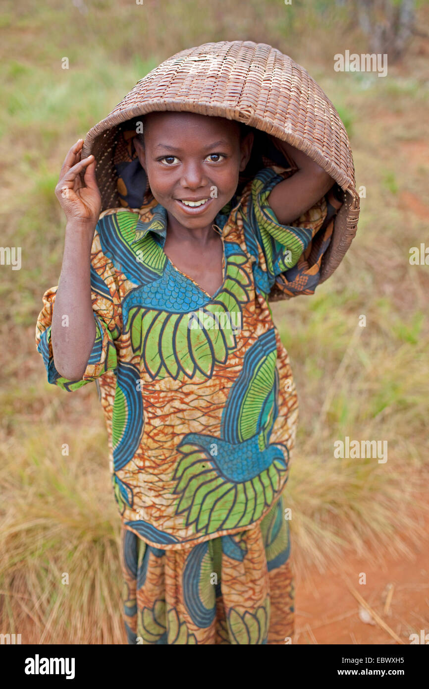 Mädchen in traditioneller Kleidung hält Korb über dem Kopf, Burundi, Karuzi, Buhiga Stockfoto