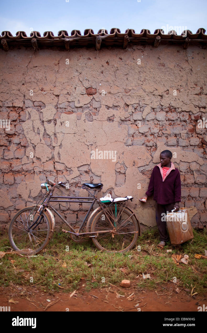 Junge mit Wasser Kanister stehen am nächsten Fahrrad Wand, Burundi, Karuzi, Buhiga Stockfoto